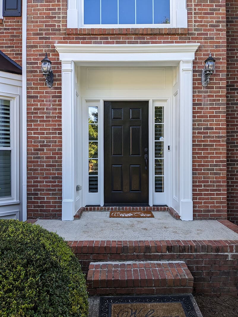 A front door of a house with brick walls.