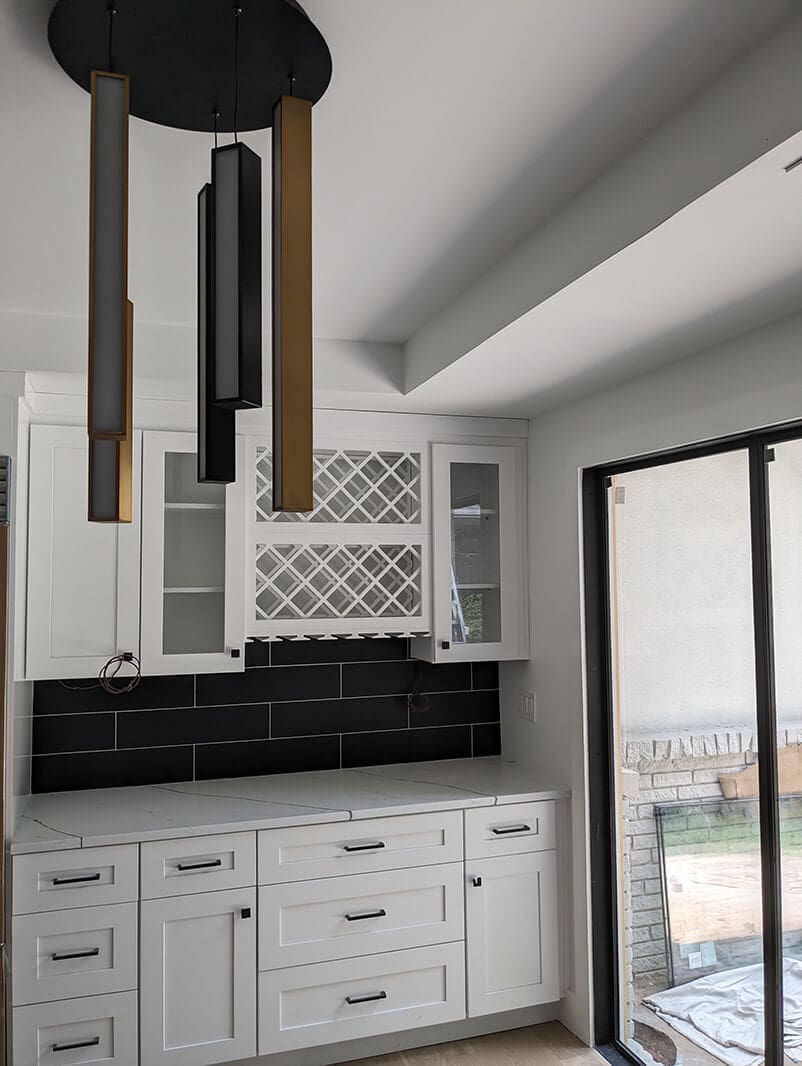 A kitchen with white cabinets and black tile.