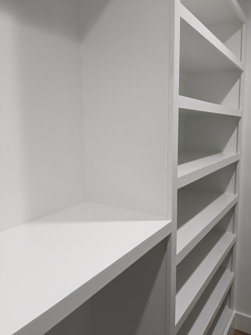A white shelf in the corner of a room.